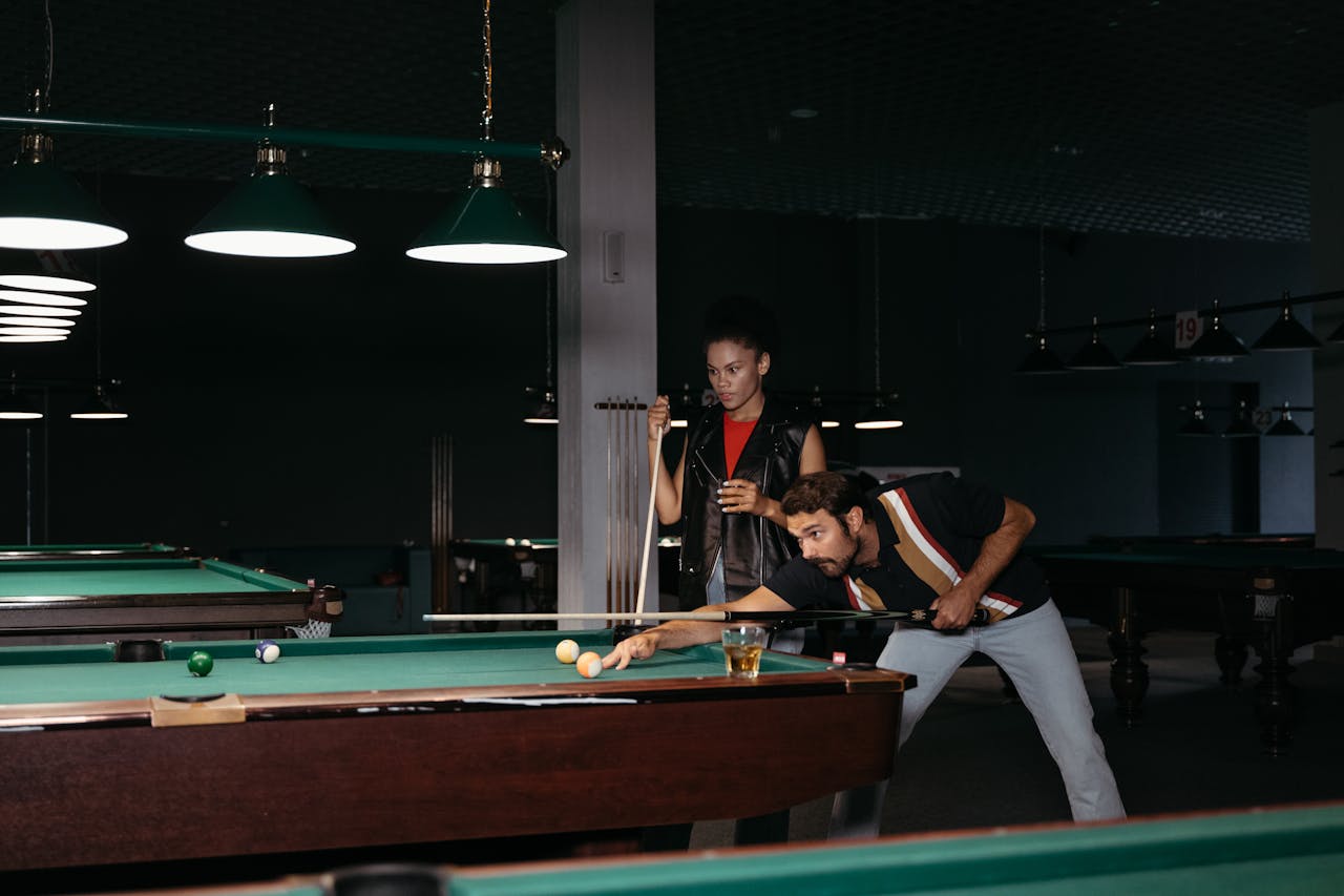 Two adults playing billiards indoors with focus and strategy.